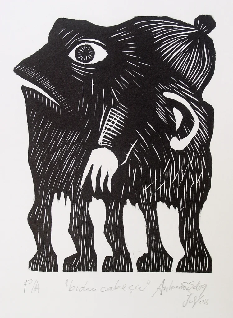 Ser com uma imensa cabeça humana, sem nariz, de onde saem cinco patas e um braço. Usa um gorro. Gravura em preto e branco. Assinatura à lápis na parte inferior: “P/A “bicho cabeça” Antonio C Silva jul/08”
